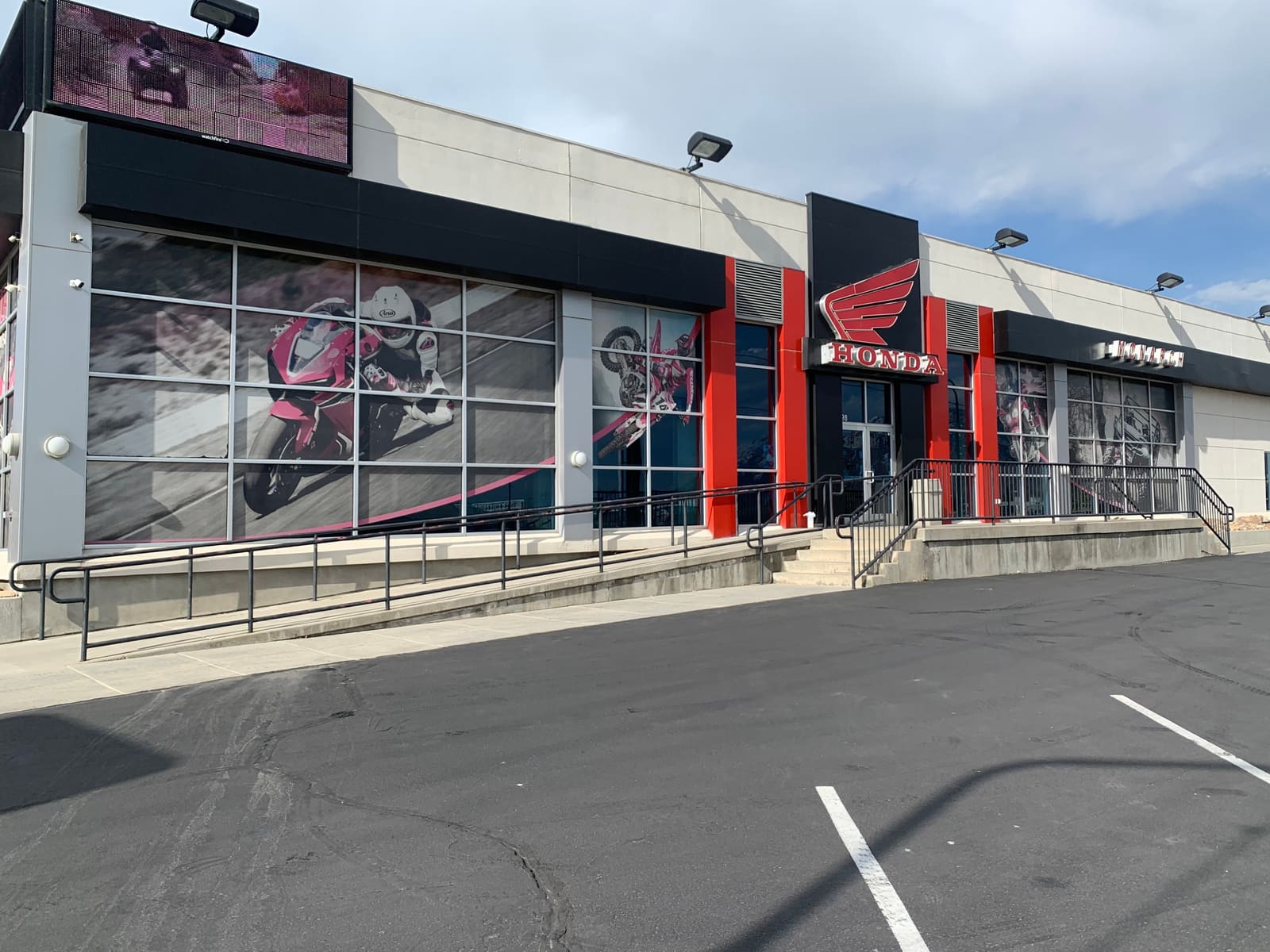 Same dealership parking lot after cleaning and striping: dark, even and clean